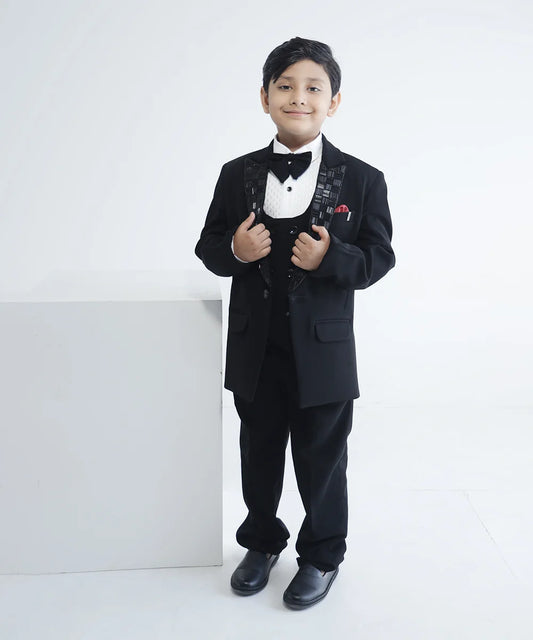 This boys wedding outfit consists of a black Colored coat, waistcoat, matching pants and a self-textured white shirt. It features a matching bow, a broach, a pocket square and beautiful work detailing on the collar that uplifts the entire look.