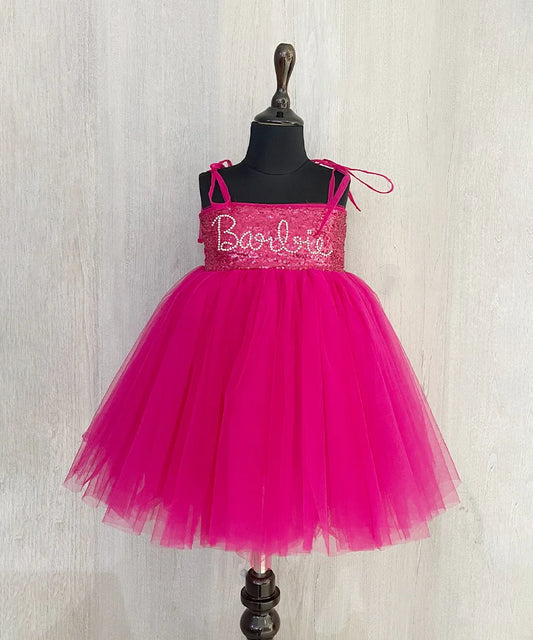 It’s a Pink colored Barbie frock that comes with a back hook closure and is perfect birthday wear for girls. It features a Barbie Inscription on the dress and an attached belt to be tied at the back curated from net fabric.