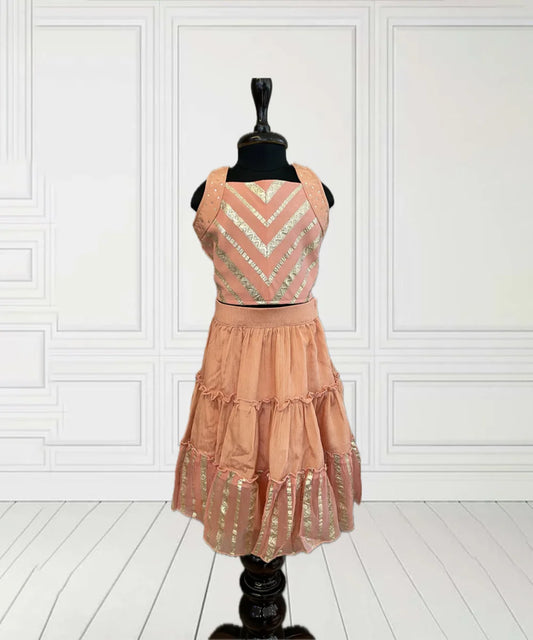 This peach coloured kids lehengas consist of a tiered skirt, a dupatta and a choli with sequin detailing on the straps. Special Feature: It features a pattern created from golden thread on the choli and the lehenga.