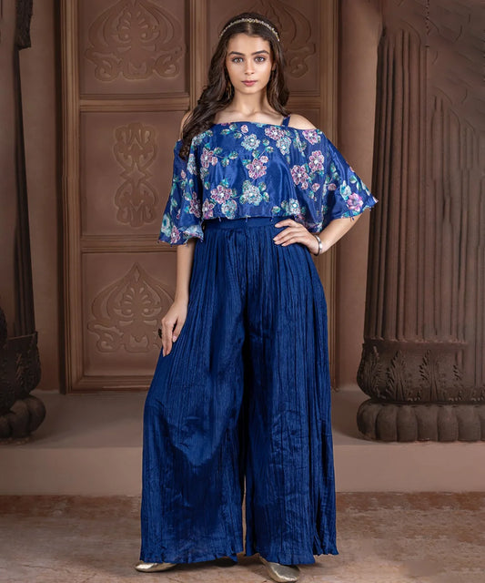 This blue coloured Indian party wear dress for kids consists of a printed cape-style top that comes with a back closure and a matching pleated sharara.