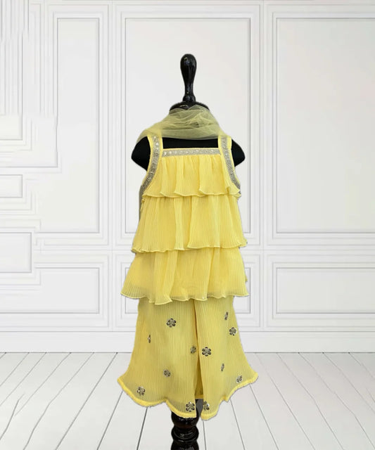 This yellow coloured baby girl sharara suit consists of a fancy layered kurta with a back button closure, a matching sharara and a dupatta. It features lace detailing on the kurta and sequin work on the sharara.