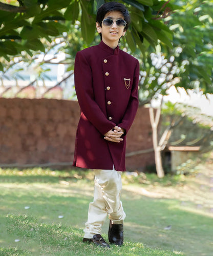 This achkan is rendered in maroon colour and paired up with a white Churidar pyjama and a nice broach. 