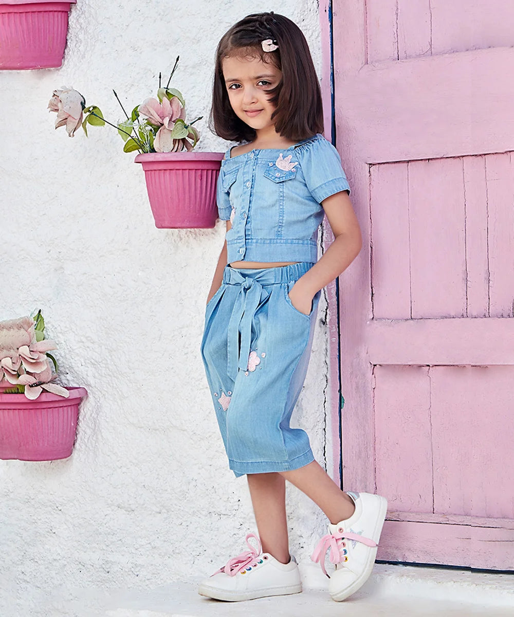  This blue Colored denim outfit Consist of a top and tie-knot pant for a kid girl. The top comes with an applique heart and star detailing. And bottom has pockets on both sides.