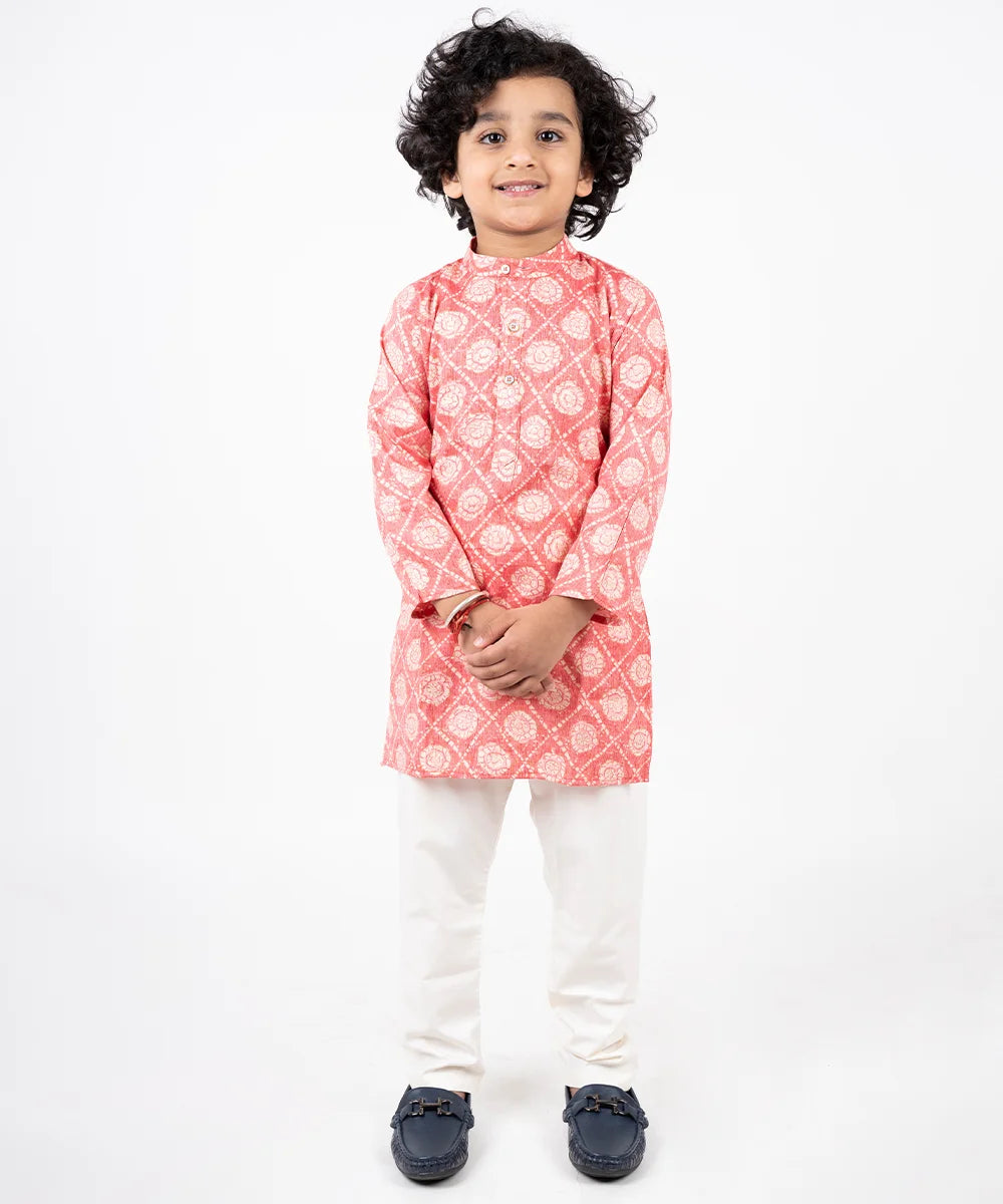 This boys' kurta-pajama set comes with a printed peach colored kurta with full sleeves and elasticated off-white colored pants