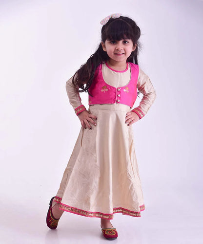 It is an A-Line beige and rani pink Colored dress that comes with a short jacket for girls. It features beautiful embroidery work on the dress.