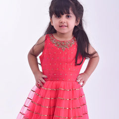 It is an elegant red party gown for girls and comes with short sleeves that can be stitched as per requirement. It features beautiful embroidery work and a matching fabric belt to be tied at the back.