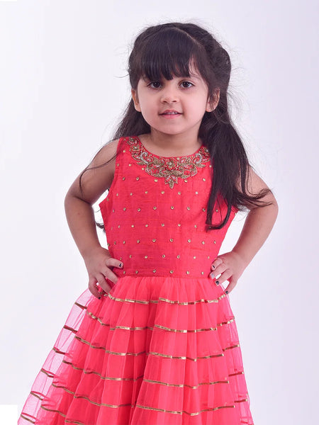 It is an elegant red party gown for girls and comes with short sleeves that can be stitched as per requirement. It features beautiful embroidery work and a matching fabric belt to be tied at the back.