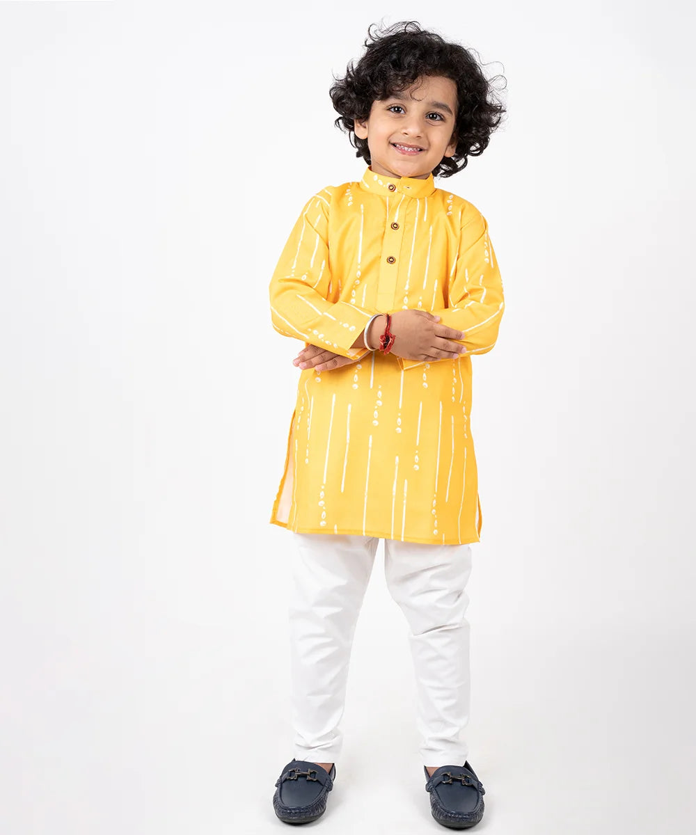 It’s a yellow printed kurta with wooden button detailing on it and paired up with matching white pants for a tailored look. 
