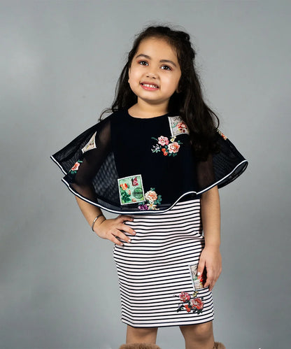  It is a navy blue Colored straight-fit dress that comes with a cape with a back zip closure and is the latest birthday dress for a girl. It features applique work and embroidery work on the cape and dress.
