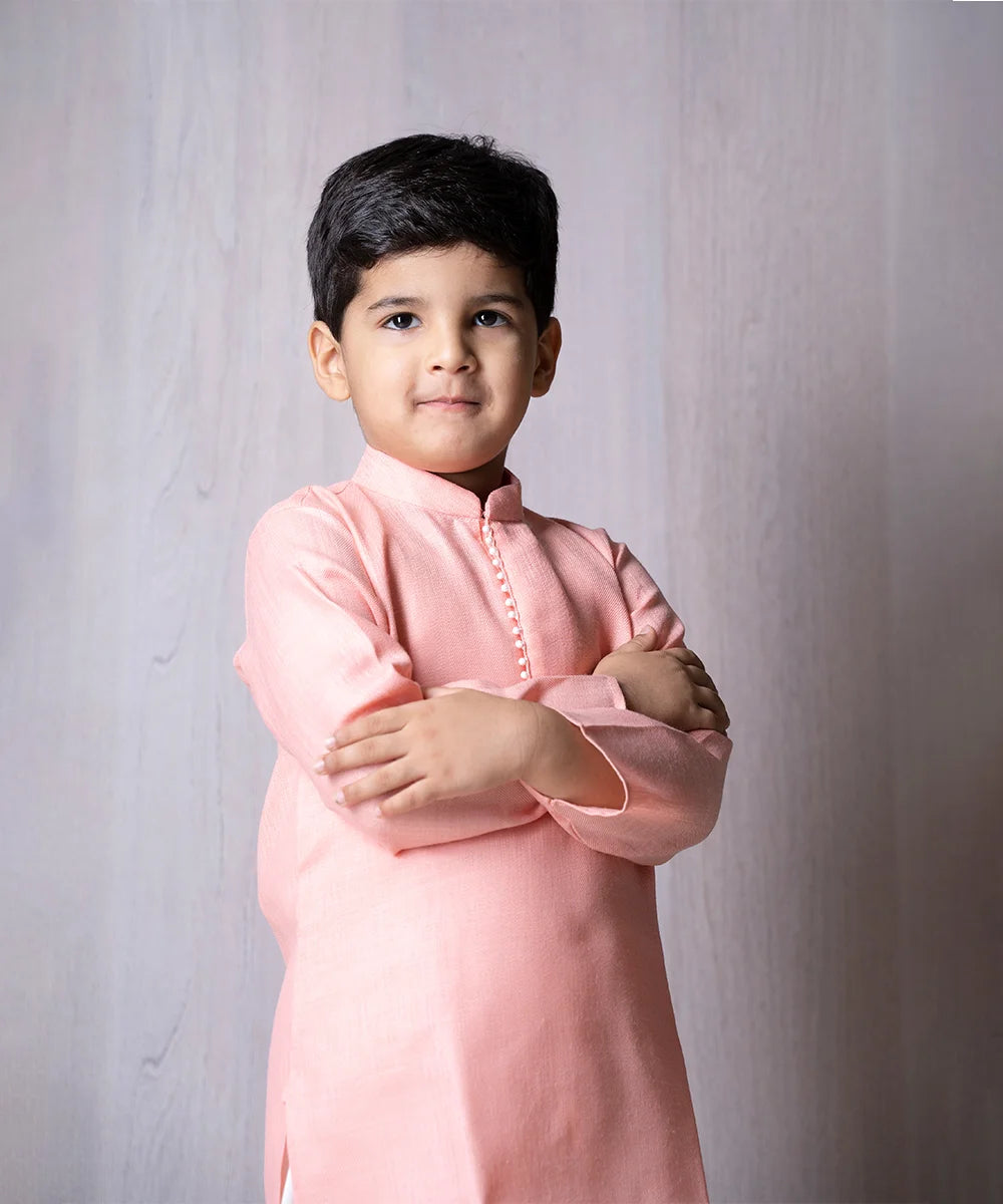 This self-textured kurta pajama set comes with a solid peach colored full sleeved kurta and white colored Salwar.