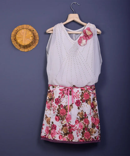  It is a pink and white floral printed western outfit for kids. It features floral detailing on the shoulder and comes with a matching ribbon belt.