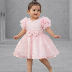 Child wearing a pink dress with fluffy sleeves on a gray background