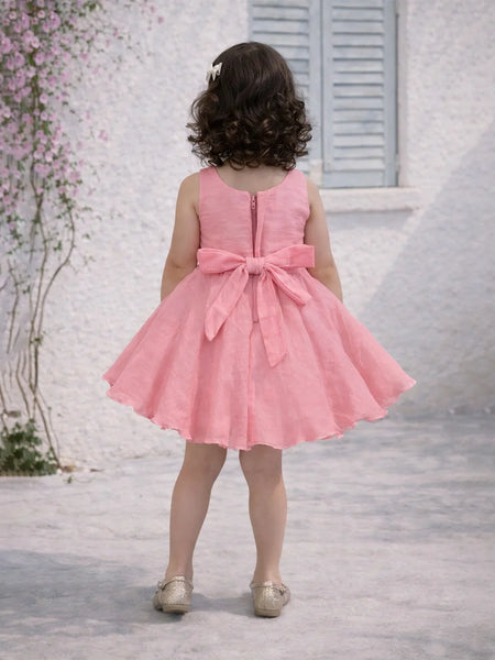 Child wearing a pink dress with a large bow in a decorative setting