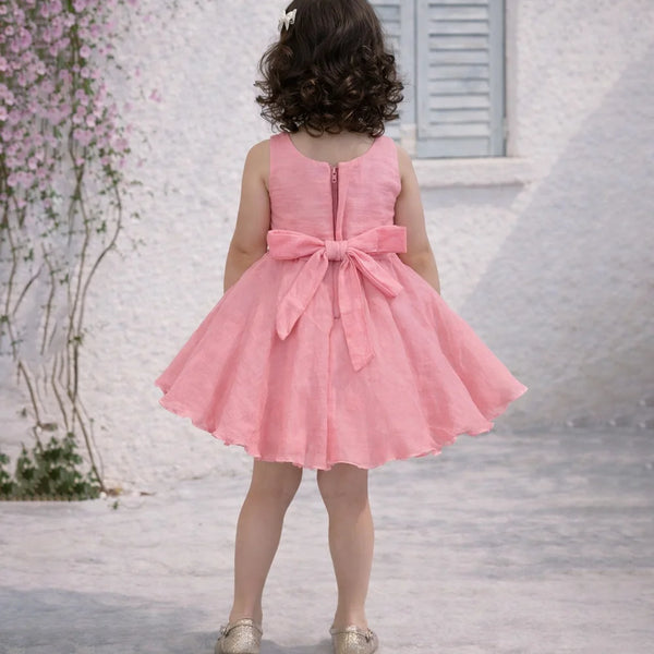 Child wearing a pink dress with a large bow in a decorative setting