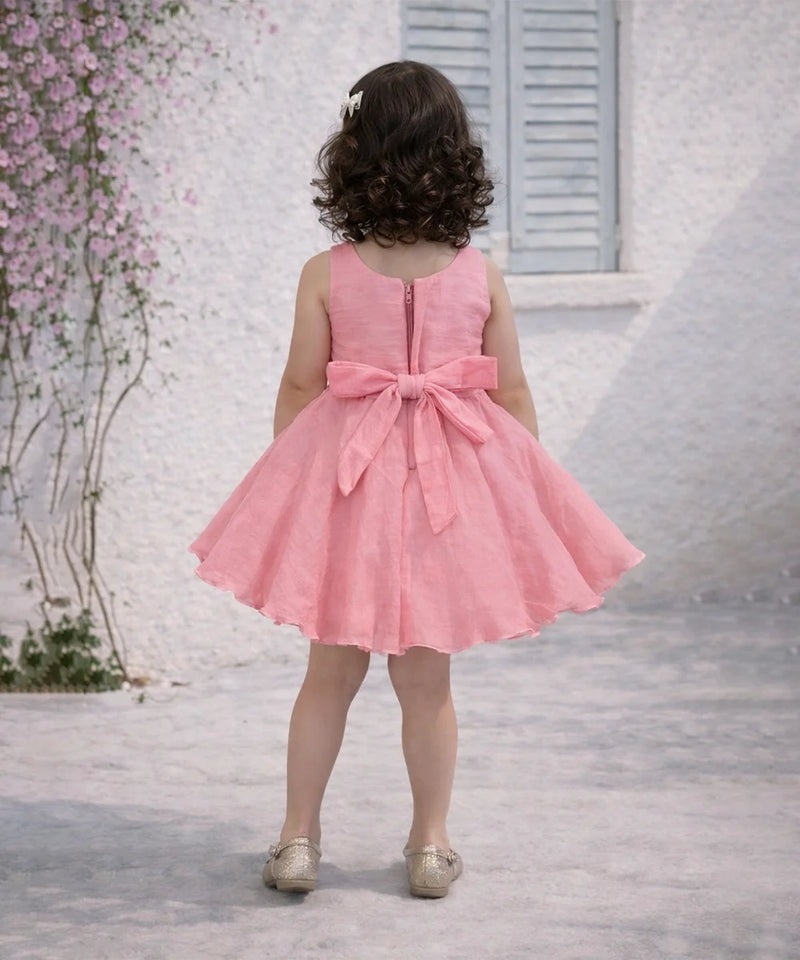 Child wearing a pink dress with a large bow in a decorative setting