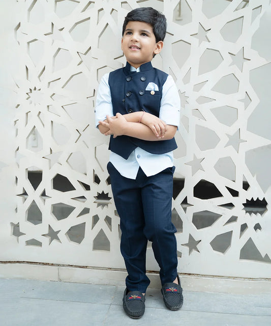It’s a navy blue coloured checked waistcoat teamed up with a light blue coloured shirt and matching pants for the party for boys. It features an asymmetric waistcoat with a cute small broach and a matching pocket square.
