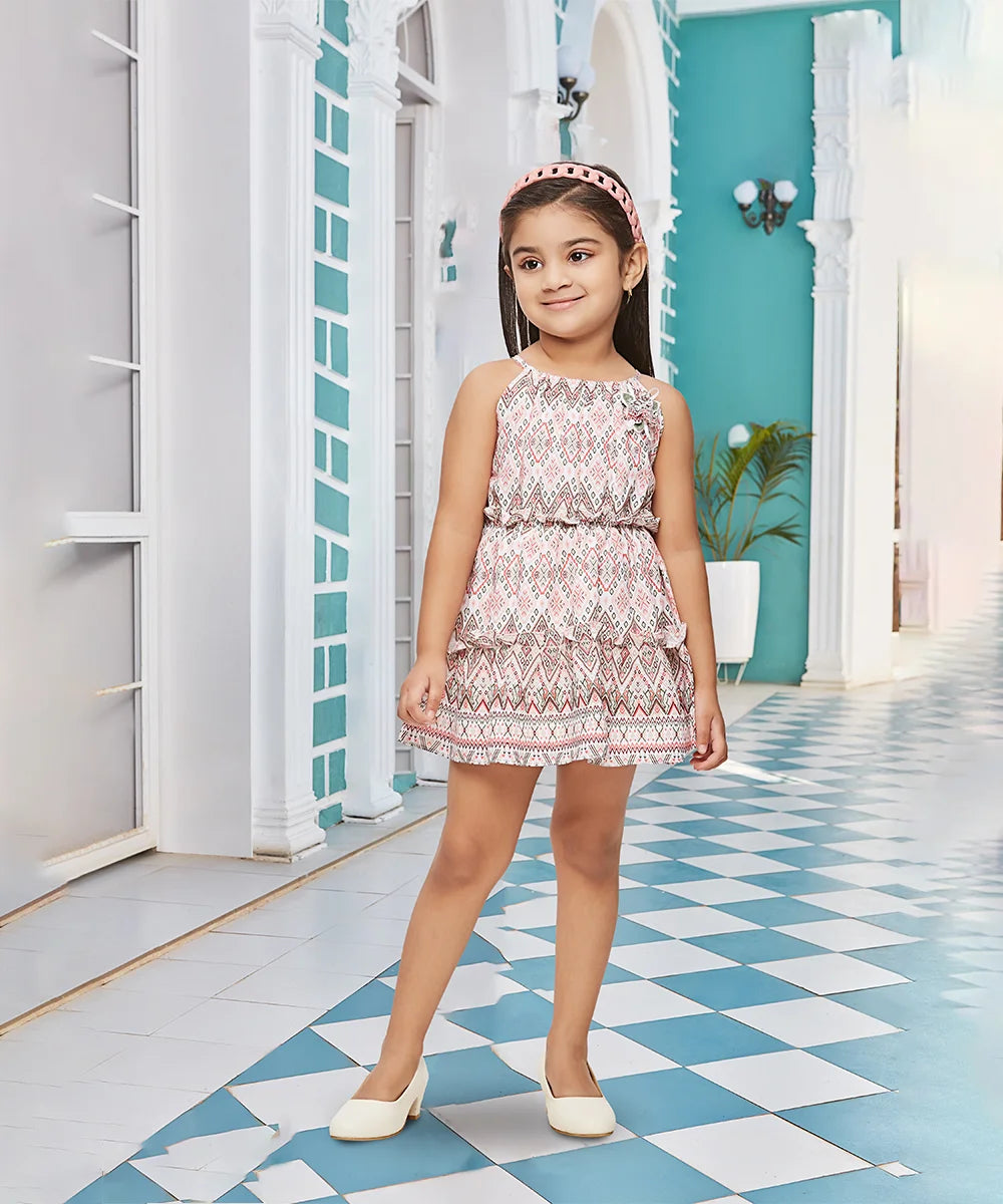It is a multi Colored self-printed tiered dress that comes with a back zip closure. It’s a trendy dress for kids. It features a cute floral broach detailing.