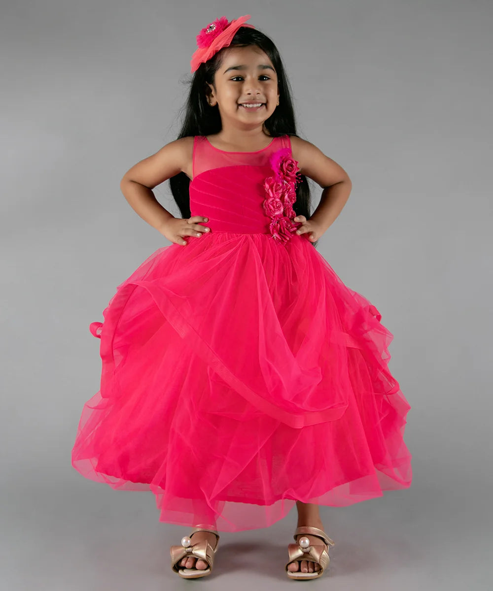 It’s a pink party gown for kid girl that comes with the back zip closure. It features floral as well as feather work on the dress and comes with the fabric belt to be tied at the back.