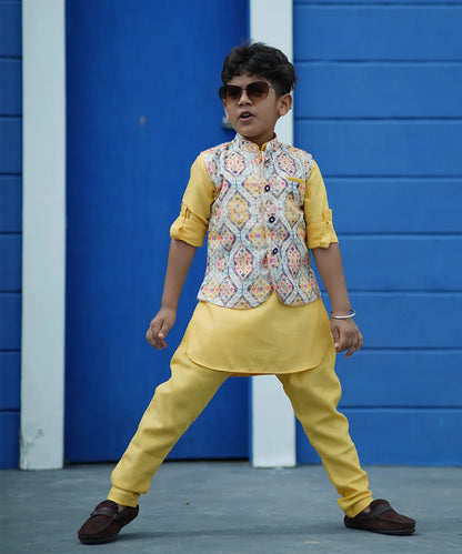 This classic yellow colored kurta set is curated from high quality fabric. It comes along with matching pajama and sleeveless printed Nehru jacket that features stylized buttons for boys. 