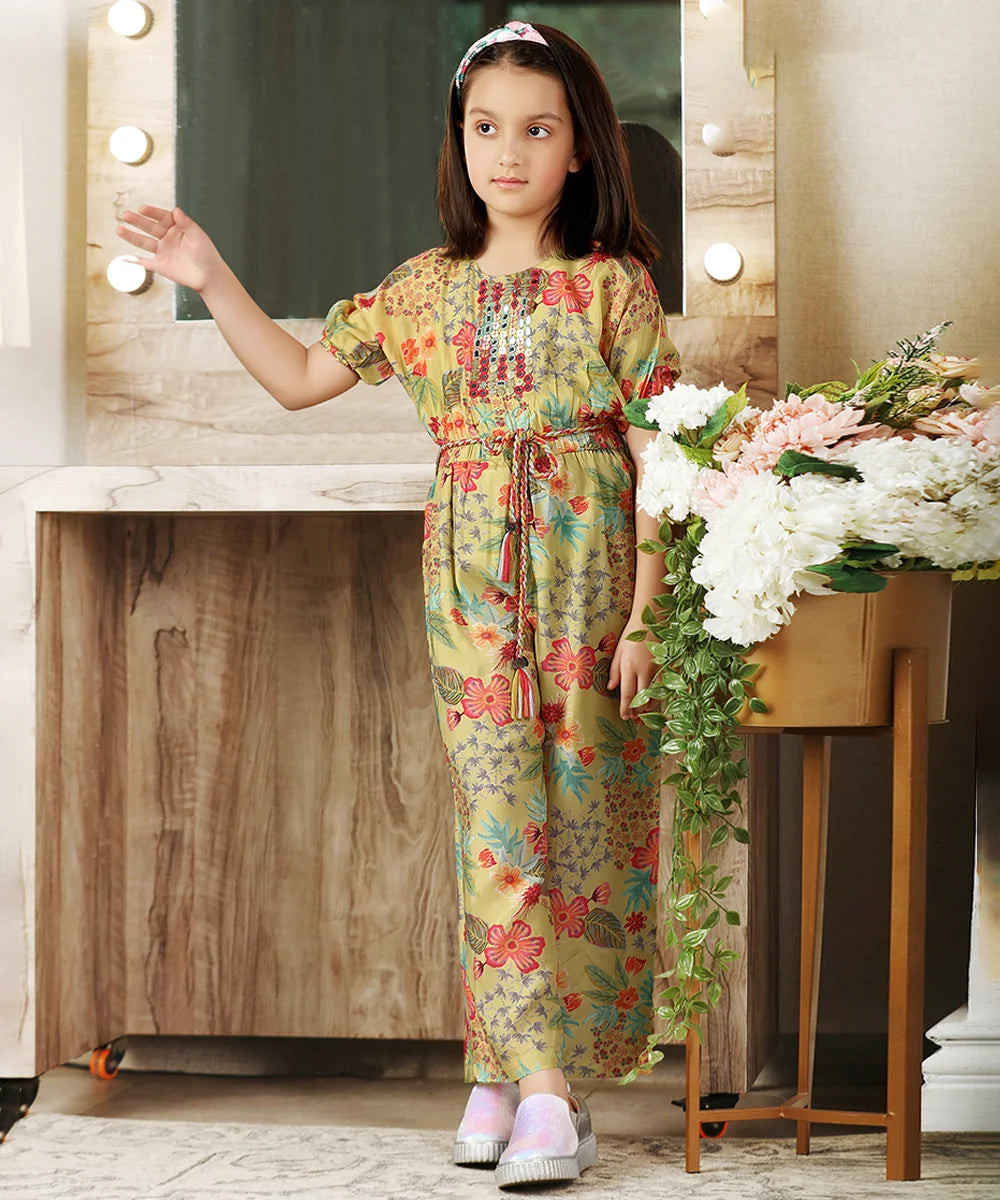 It is a yellow Colored floral printed jumpsuit that comes with an elasticated waist and a matching string belt to be tied on the waist. This outfit comes with Mirror work detailing in the front and a zip closure at the back.