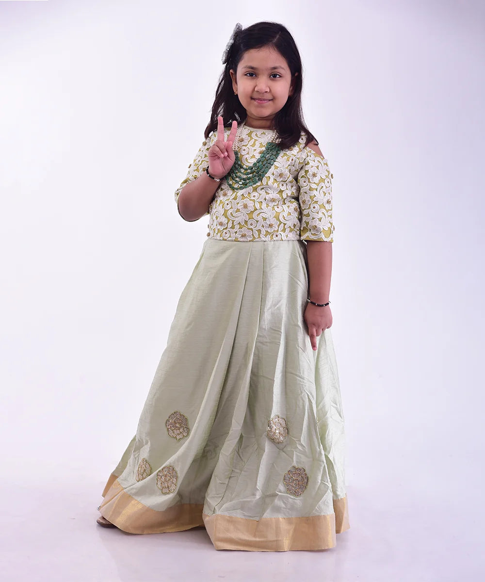 This green dress consist of an embroidered choli, a Lehenga and a dupatta for your kids with a back hook closure. It features applique work and lace detailing on Lehenga.