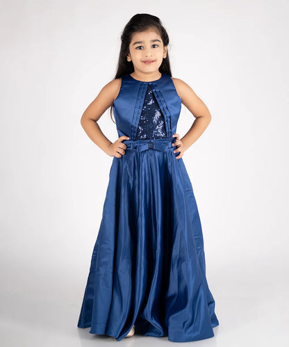 This navy blue Colored long gown for girls that comes with a back zip closure. It features sequin fabric, pleated detailing and a matching bow on the waist.