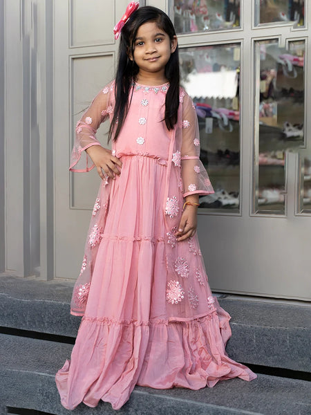 This pink Colored party wear clothes consists of a tiered gown that comes with the back zip closure and a shrug. It features bead work and mirror work done on floral motif.