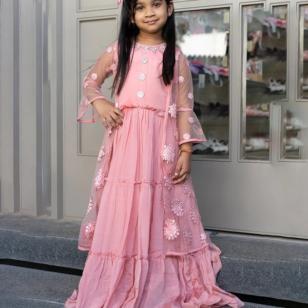 This pink Colored party wear clothes consists of a tiered gown that comes with the back zip closure and a shrug. It features bead work and mirror work done on floral motif.