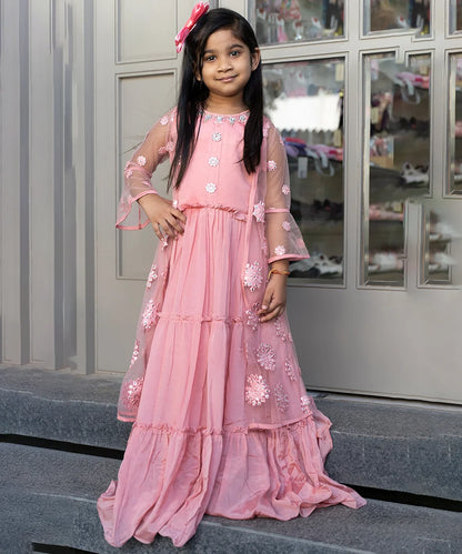 This pink Colored party wear clothes consists of a tiered gown that comes with the back zip closure and a shrug. It features bead work and mirror work done on floral motif.