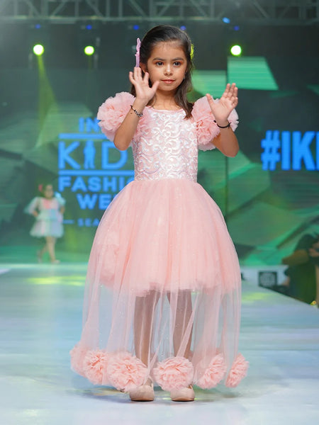 It’s a fancy pink Colored gown for girls that comes with the ruffle sleeves and back zip closure.  It features big flower detailing and the fabric belt to be tied at the back.