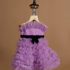 It’s a purple Colored frock with lots of frill and pleated detailing. It features black velvet belt and pearl detailing on the dress.