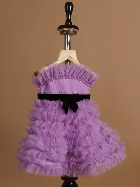 It’s a purple Colored frock with lots of frill and pleated detailing. It features black velvet belt and pearl detailing on the dress.