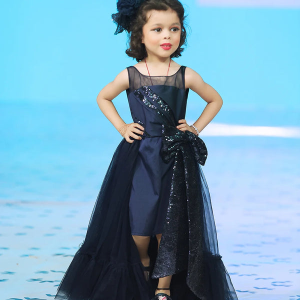 It’s a beautiful navy gown for kids with trail that comes with the back zip closure. It features big sequin bow on the waist and pleated detailing on the yoke that adds grace to the look.