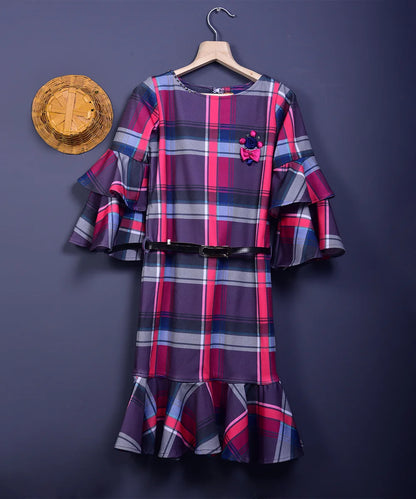 It is a multi Colored checked dress with a white belt for girls. This dress comes with floral and stone detailing and the belt has a written inscription on it.