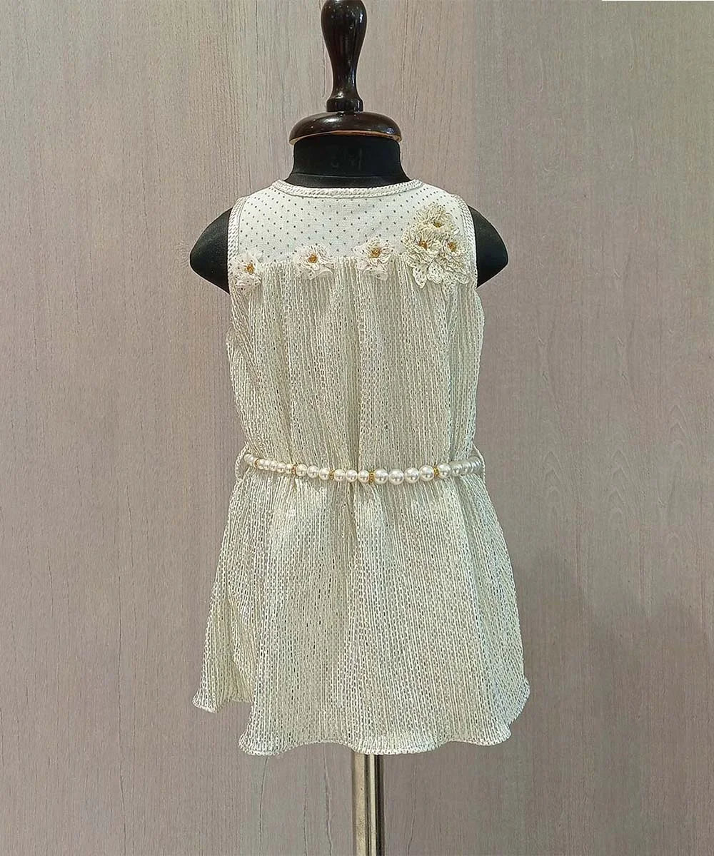 It is a white birthday dress with a back zip closure. It featured cute floral detailing on the yoke and a pearl belt to add grace to the dress.