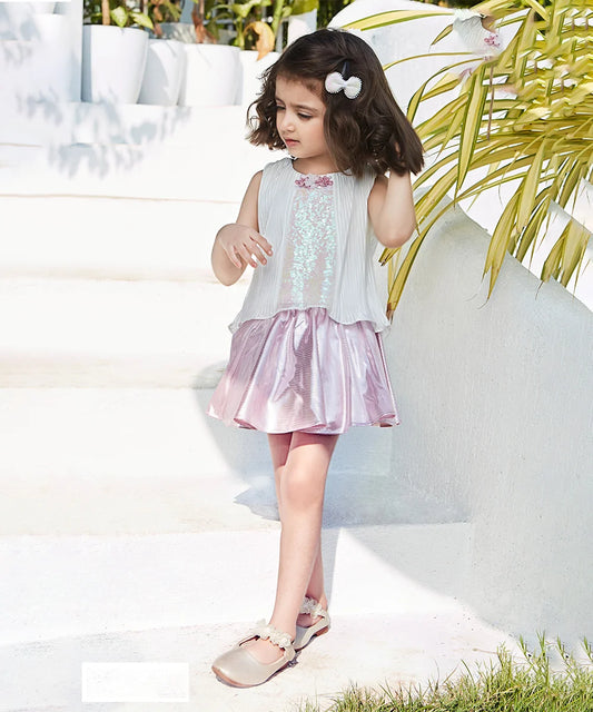 This white and pink Colored outfit Consists of a high-low top with a silver dotted skirt for a kid girl. The top comes with a beautiful sequin and floral detailing.