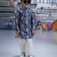 It is a full sleeve indigo blue Colored printed kurta paired up with a cream coloured pyjama. This kurta curated from raw silk fabric that features thread detailing done on collar and placket while the pyjama features an elasticated waist to keep him at ease.