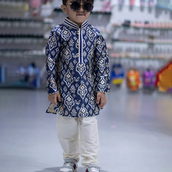 It is a full sleeve indigo blue Colored printed kurta paired up with a cream coloured pyjama. This kurta curated from raw silk fabric that features thread detailing done on collar and placket while the pyjama features an elasticated waist to keep him at ease.