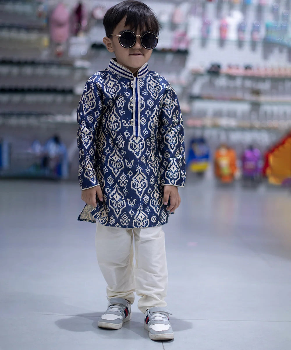 It is a full sleeve indigo blue Colored printed kurta paired up with a cream coloured pyjama. This kurta curated from raw silk fabric that features thread detailing done on collar and placket while the pyjama features an elasticated waist to keep him at ease.
