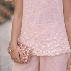 Person wearing a pink dress with a textured pattern, holding a matching pink clutch.