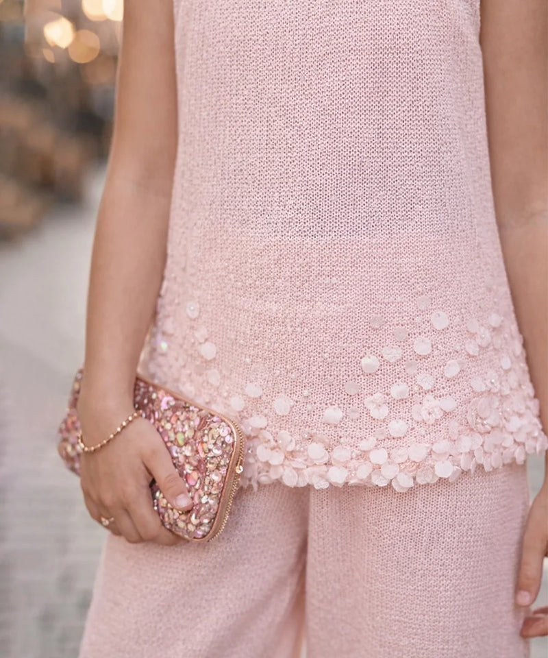 Person wearing a pink dress with a textured pattern, holding a matching pink clutch.