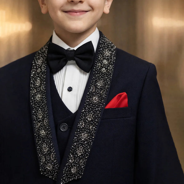 Young boy in a formal tuxedo with a red handkerchief against a warm-toned background