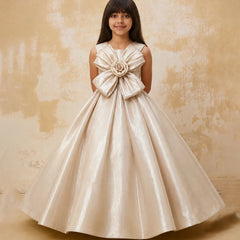 Young girl in a beige formal dress with a large bow on a textured beige background