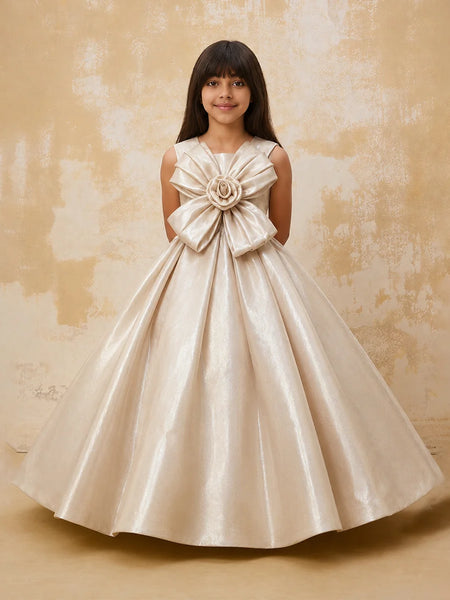 Young girl in a beige formal dress with a large bow on a textured beige background