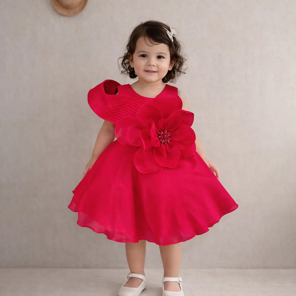 Child wearing a red dress with floral details against a plain background