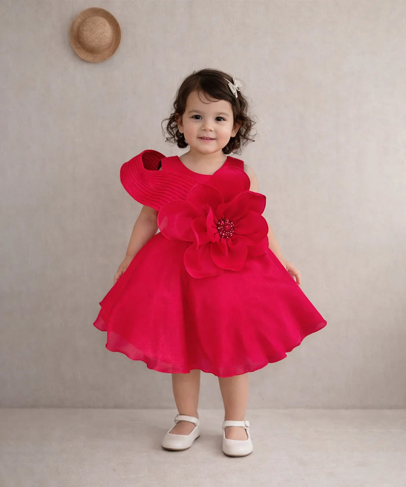 Child wearing a red dress with floral details against a plain background