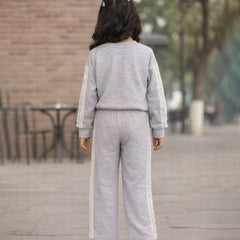 Person wearing a gray tracksuit with white stripes outdoors on a wooden deck.