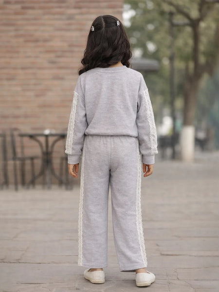 Person wearing a gray tracksuit with white stripes outdoors on a wooden deck.