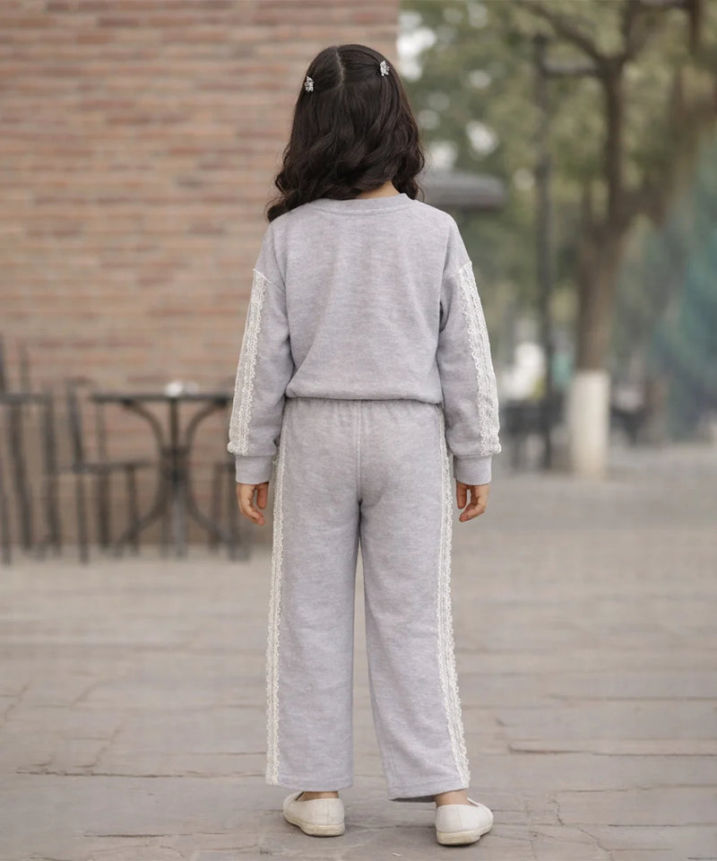 Person wearing a gray tracksuit with white stripes outdoors on a wooden deck.