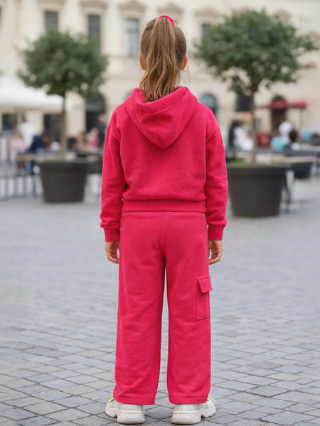 Person wearing a pink tracksuit standing on a paved area with blurred background
